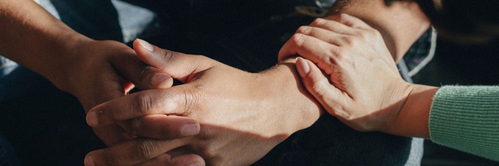 woman setting her hand over a man's to support and comfort him