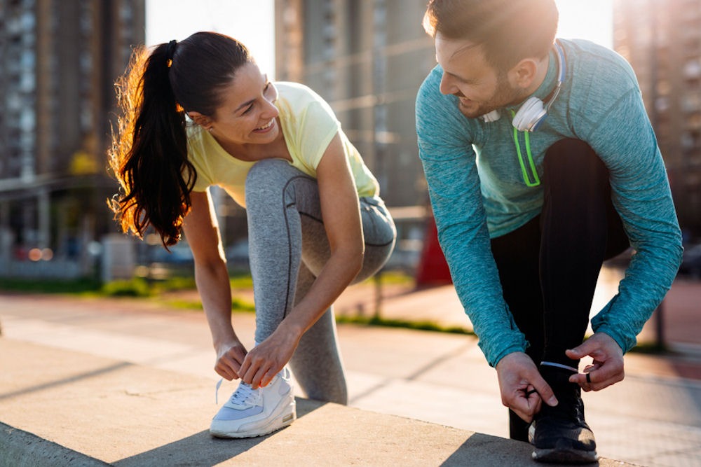 couple tying their shoes to go on a run together in the city