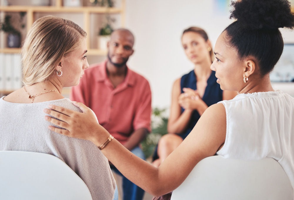 three women and one man sitting together discussing mental health