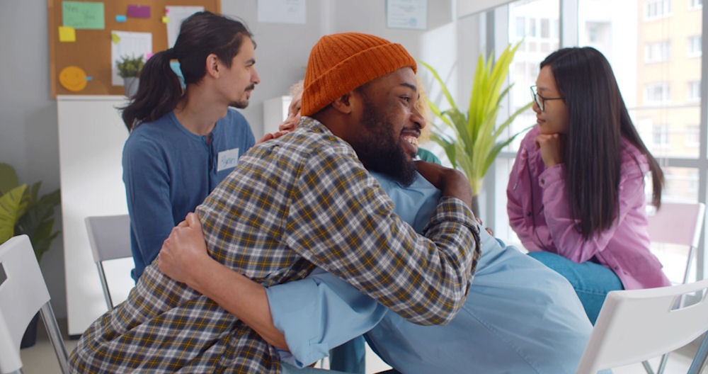 Diverse smiling people hugging in support group meeting