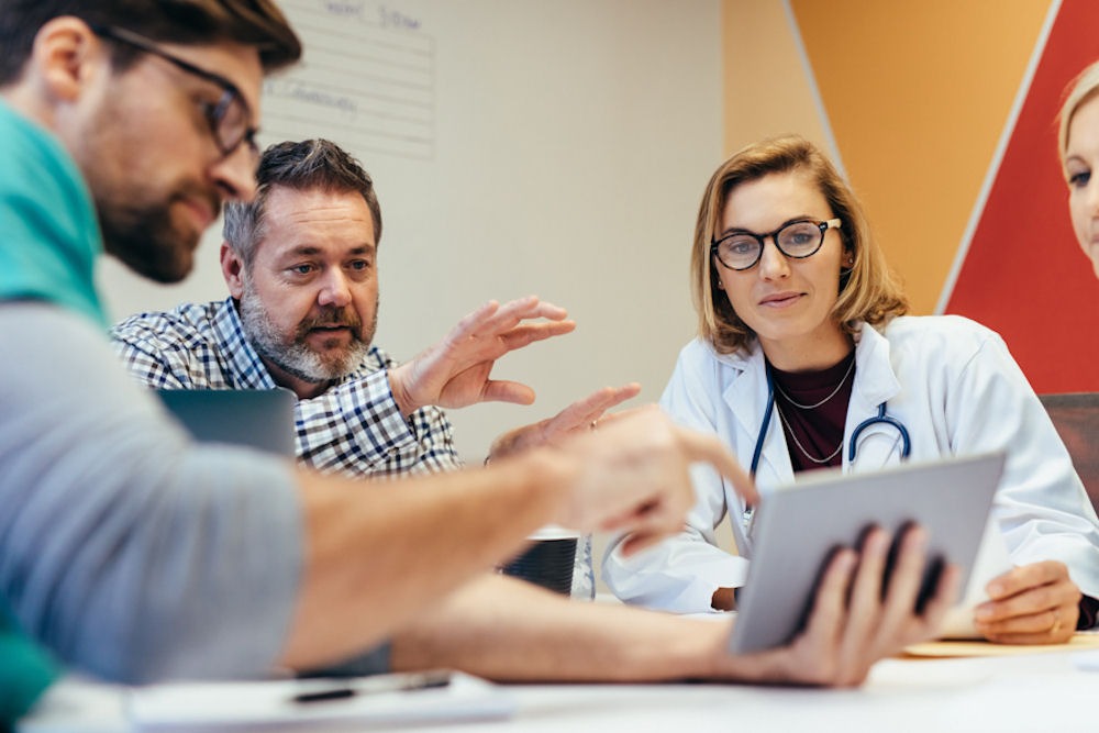 team of medical professionals reviewing a treatment plan on a tablet