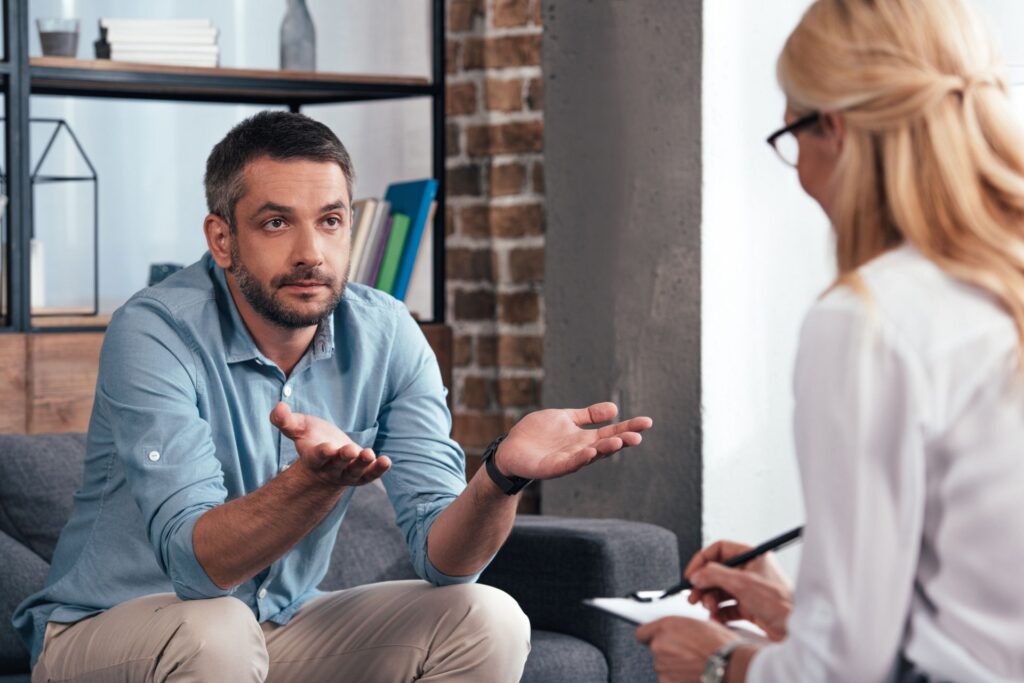 man with his hands up asking for advice from therapist while he's in individual therapy