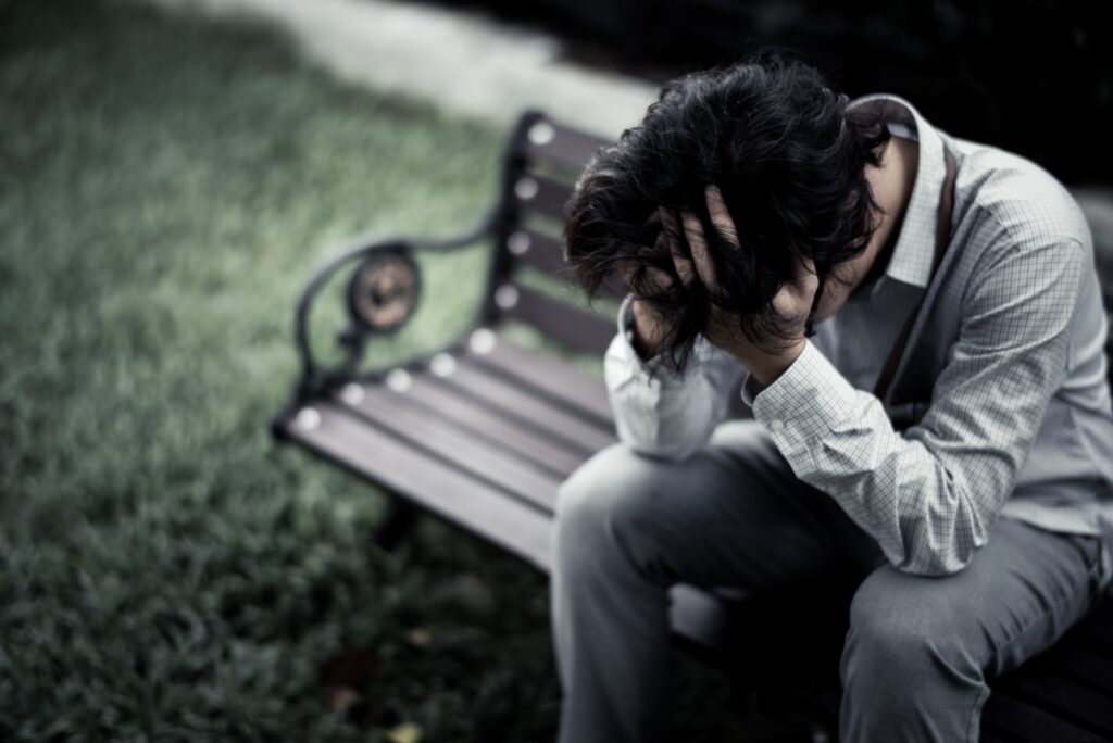 man sitting on a bench with head in hands