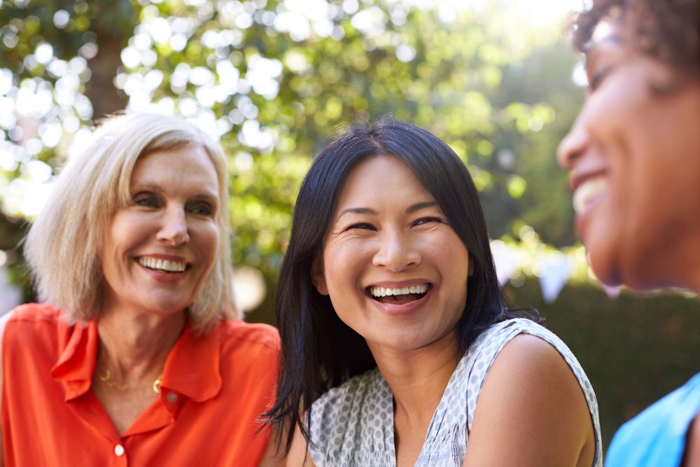 Women laughing together outdoors, coping with loneliness during the holidays