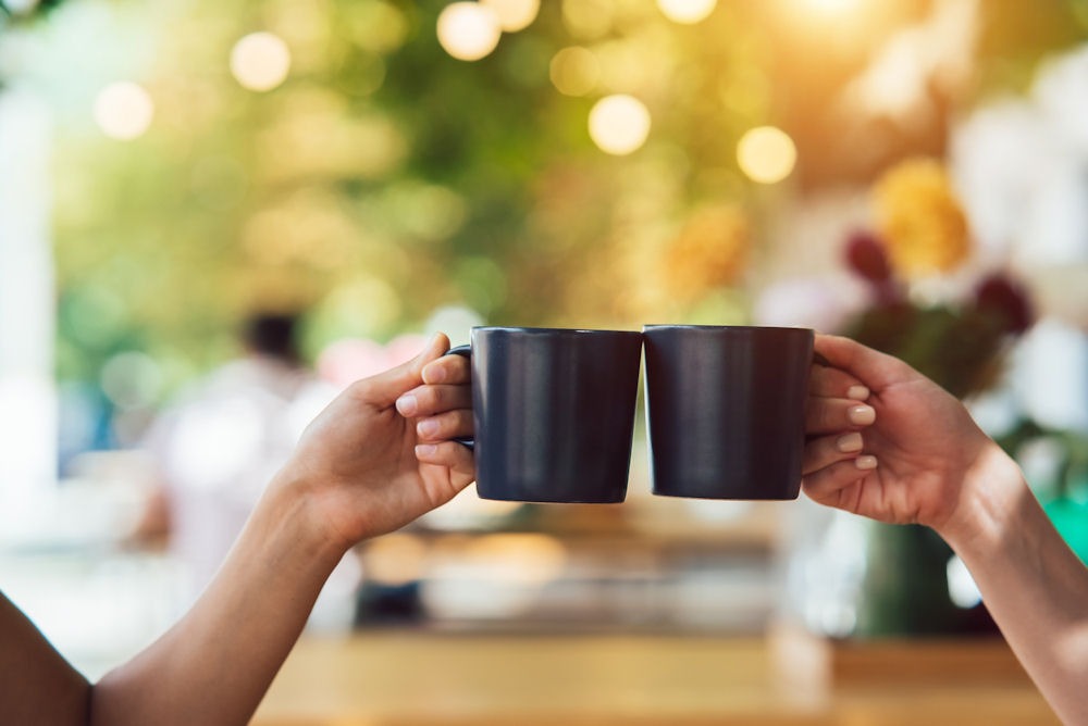 Two people toasting with coffee mugs, highlighting Dry January health benefits